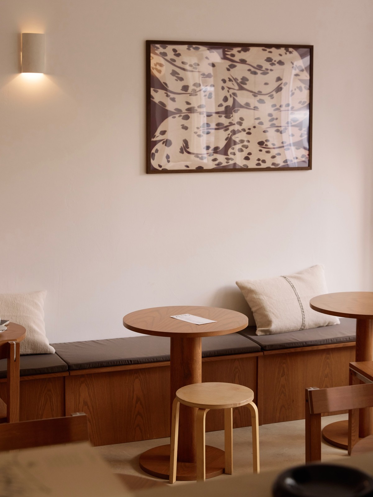 Nouvelle banquette en bois et tables bistrot sous le grand tableau mural