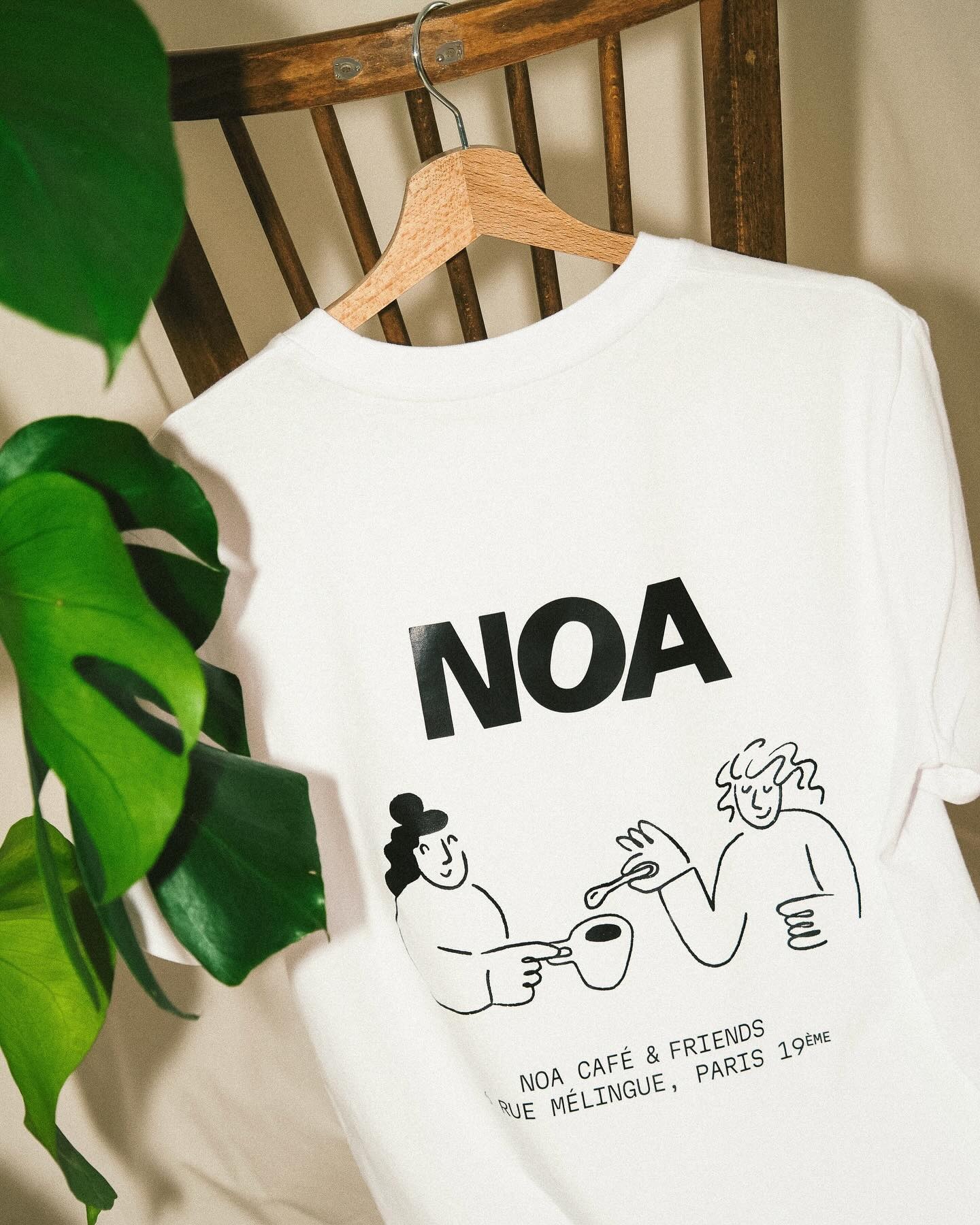 T-shirt officiel NOA Café 100% coton bio sur chaise avec monstera
