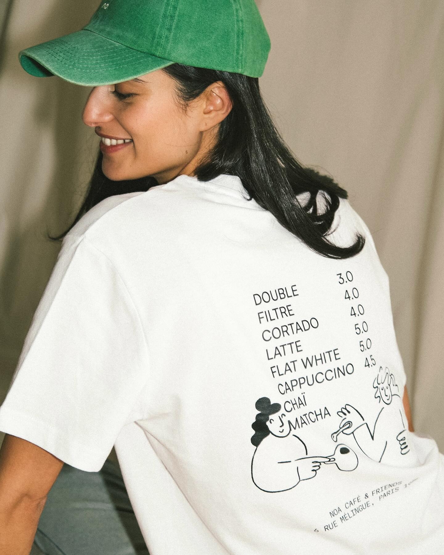 T-shirt blanc NOA Café porté de dos avec casquette verte et carte des cafés