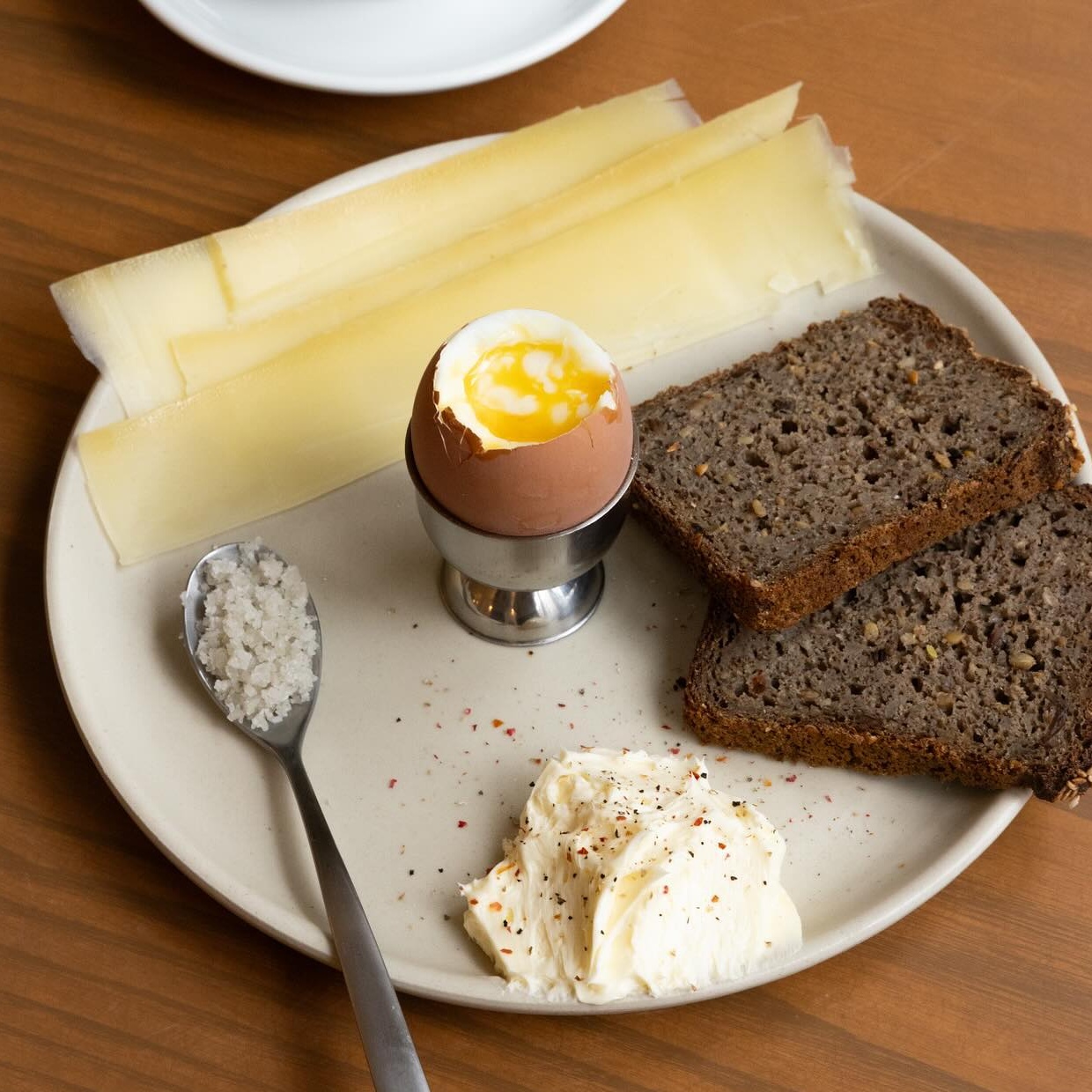 Petit déjeuner scandinave NOA avec œuf coque, comté, pain noir et beurre fouetté